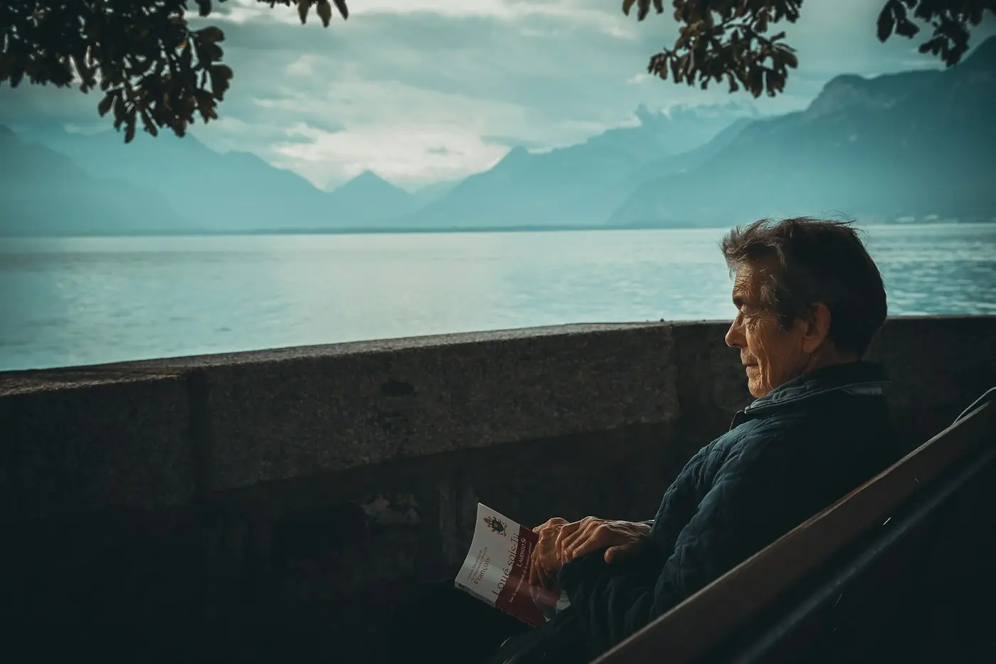 Hombre adulto sentado frente a un lago, mirando el horizonte en calma